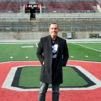 Man on football field smiling for camera.